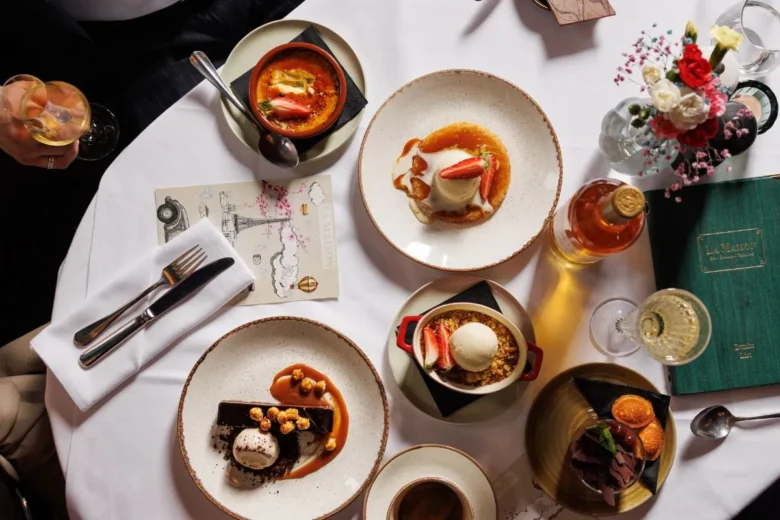 Top view of assorted French desserts at La Maison Dublin with elegant plating, wine, and floral table setting.