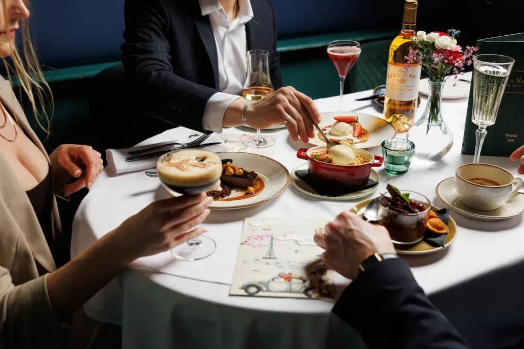 Guests sharing French desserts and cocktails at La Maison Dublin in a refined dining setting.