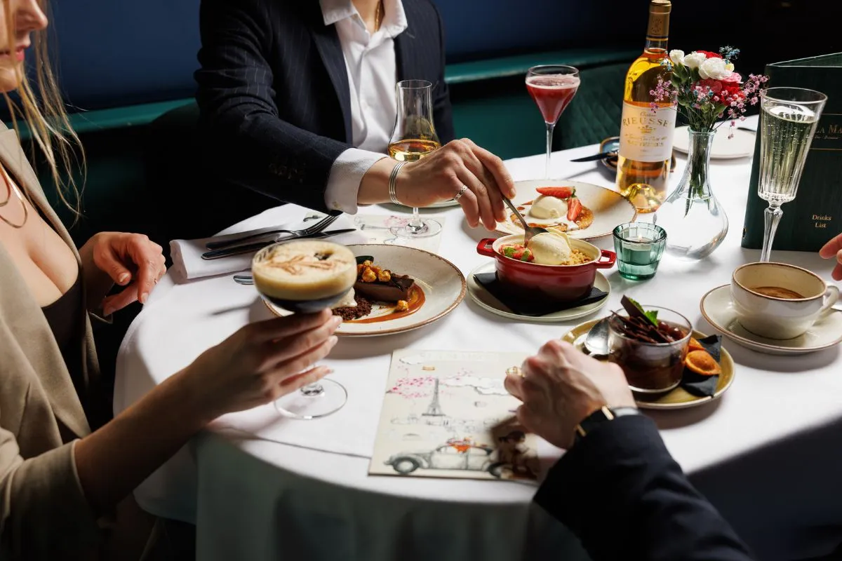 Guests sharing French desserts and cocktails at La Maison Dublin in a refined dining setting.