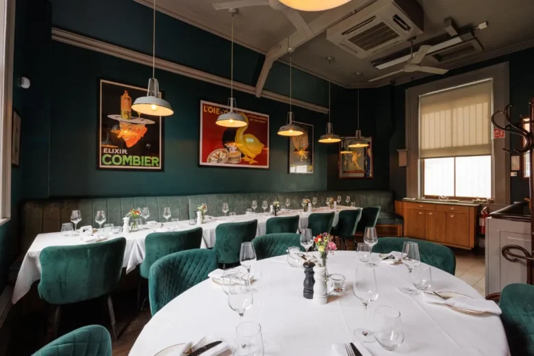 Chic private dining area at La Maison Dublin featuring emerald green chairs and classic French poster art.