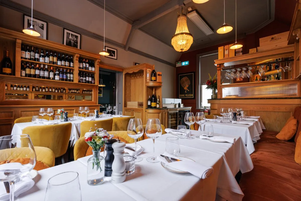 Private dining room at La Maison Dublin with elegant table settings, wine display, and arched windows.