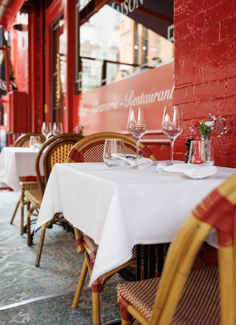 Outdoor terrace seating at La Maison Dublin with elegant table setup and red exterior walls.