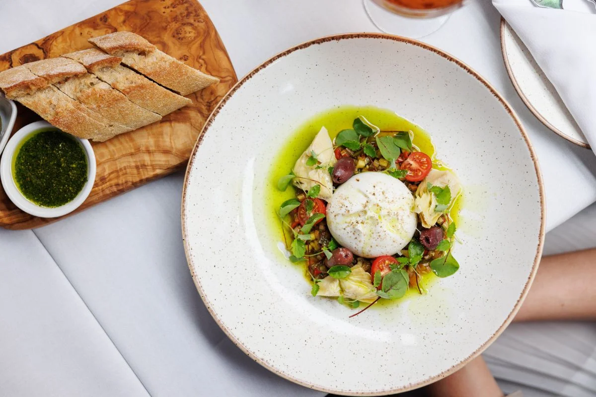 Fresh salad with burrata, cherry tomatoes, olives and bread on the side