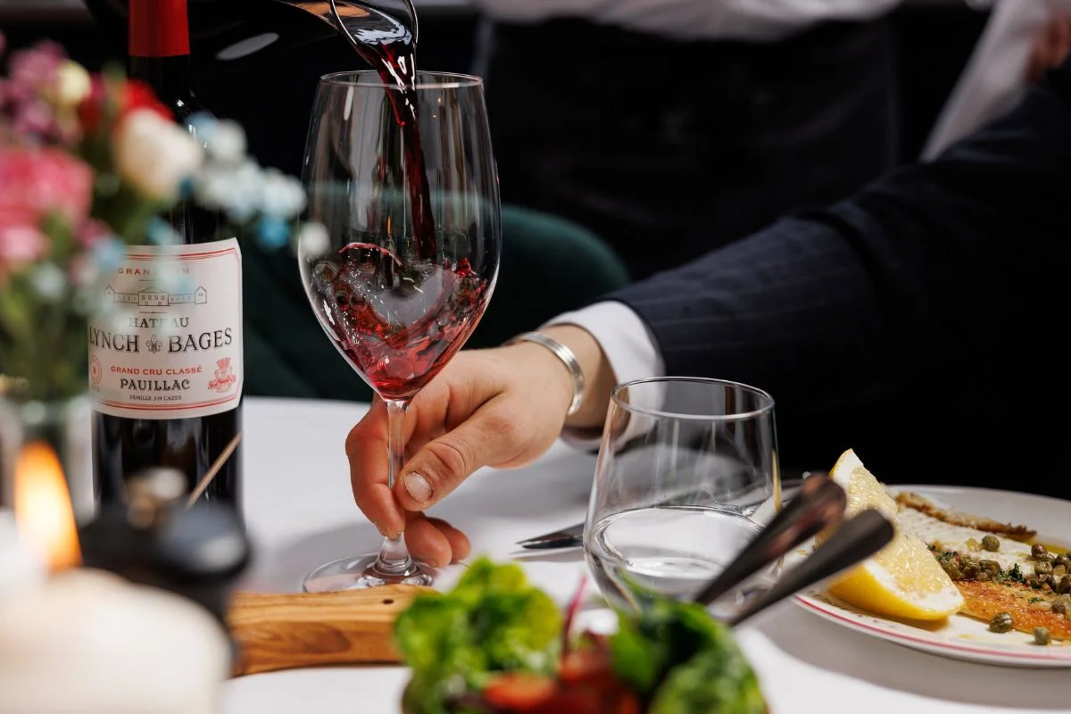 Red wine being poured into a glass during a fine dining experience